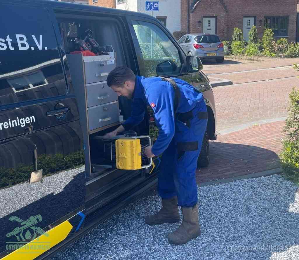 Een monteur pakt buiten op de oprit gereedschap uit de bedrijfsbus, het moment om een professional in te schakelen voor een verstopte afvoer in Mijdrecht