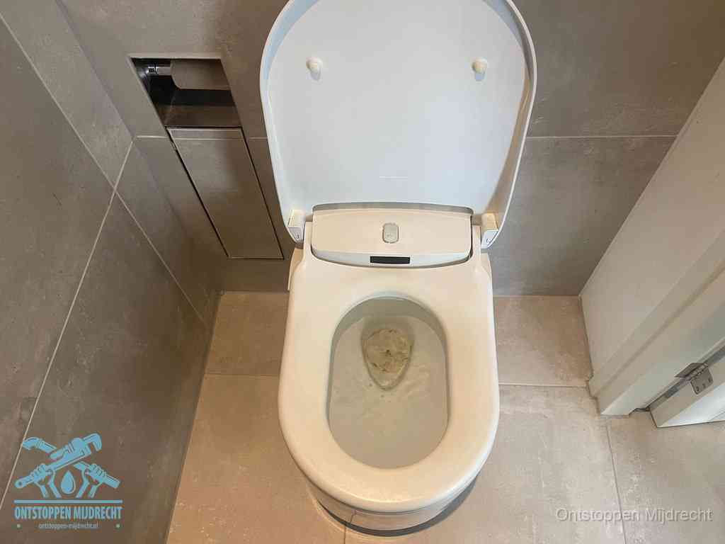 Een wit hangtoilet waarin een prop wc-papier op het water blijft drijven, een duidelijk signaal van een verstopte wc in Mijdrecht