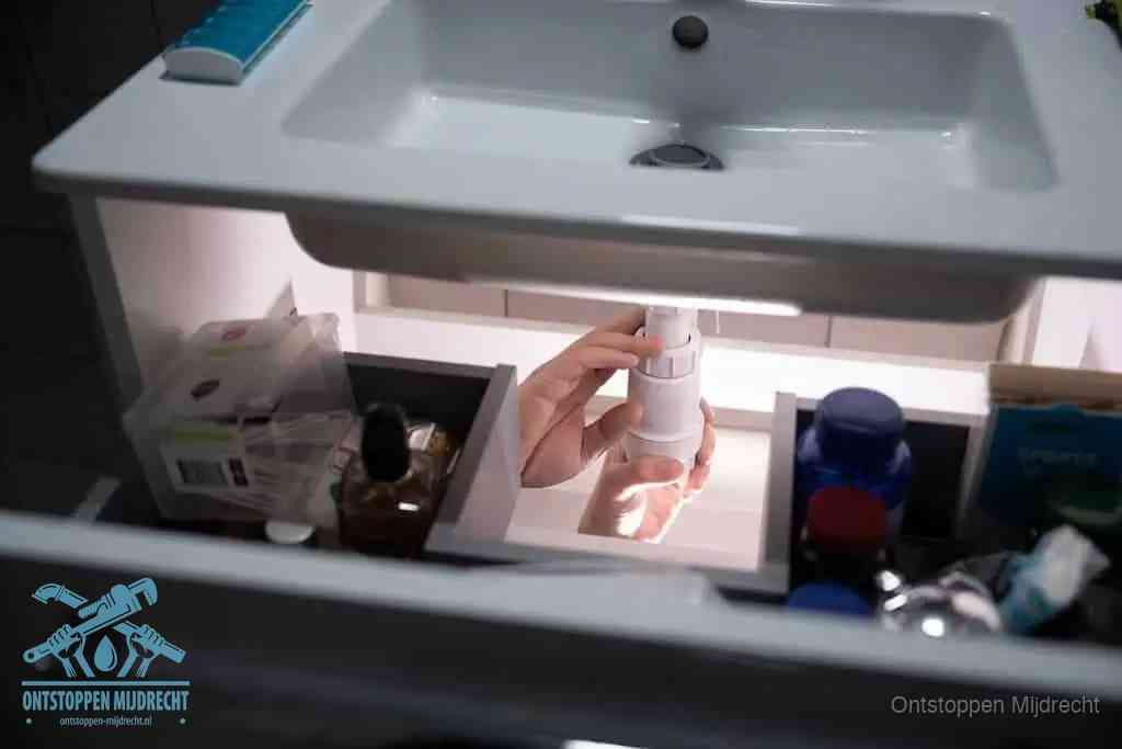 Een pompfles met zeep boven een wastafel in de toiletruimte, de warm water en afwasmiddel-methode om de wc te ontstoppen in Mijdrecht